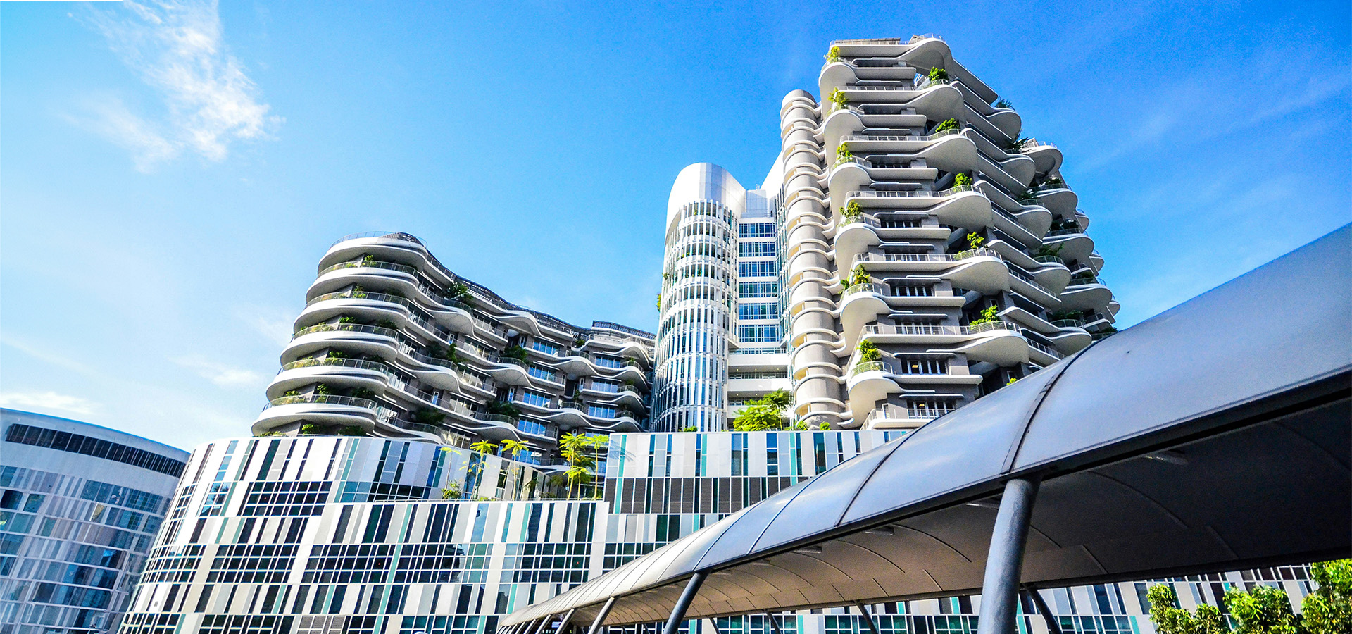 Modernes, mehrstöckiges Gebäude mit gewellten Balkonen und Begrünung – repräsentativ für nachhaltige Immobilieninvestments im Portfolio von ENIGMA GmbH.