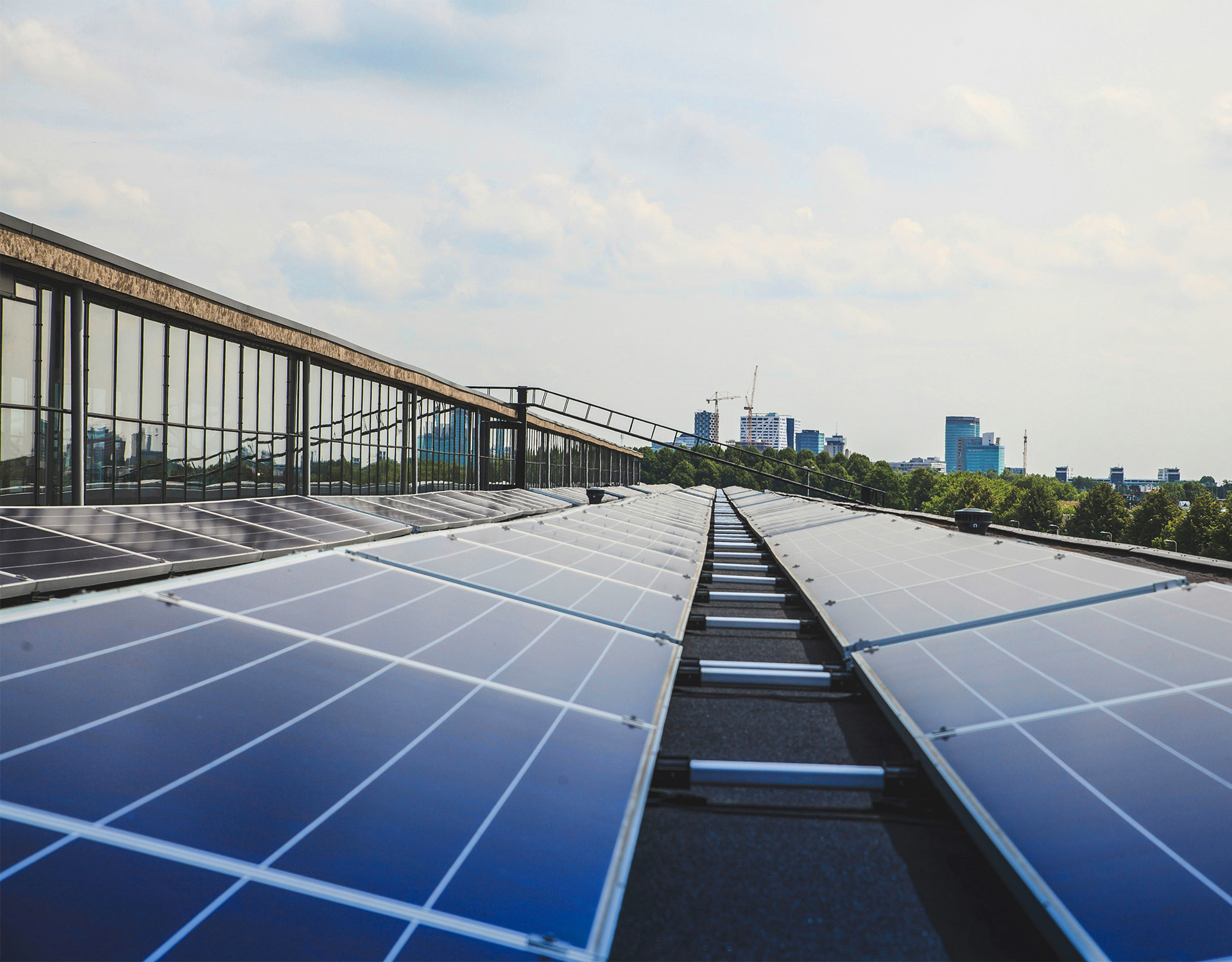 Solarpaneele auf einem Dach mit Stadtblick – repräsentiert den Photovoltaik-Fokus von ENIGMA GmbH, einem internationalen Consulting- und Investmentunternehmen für Immobilien und erneuerbare Energien.
