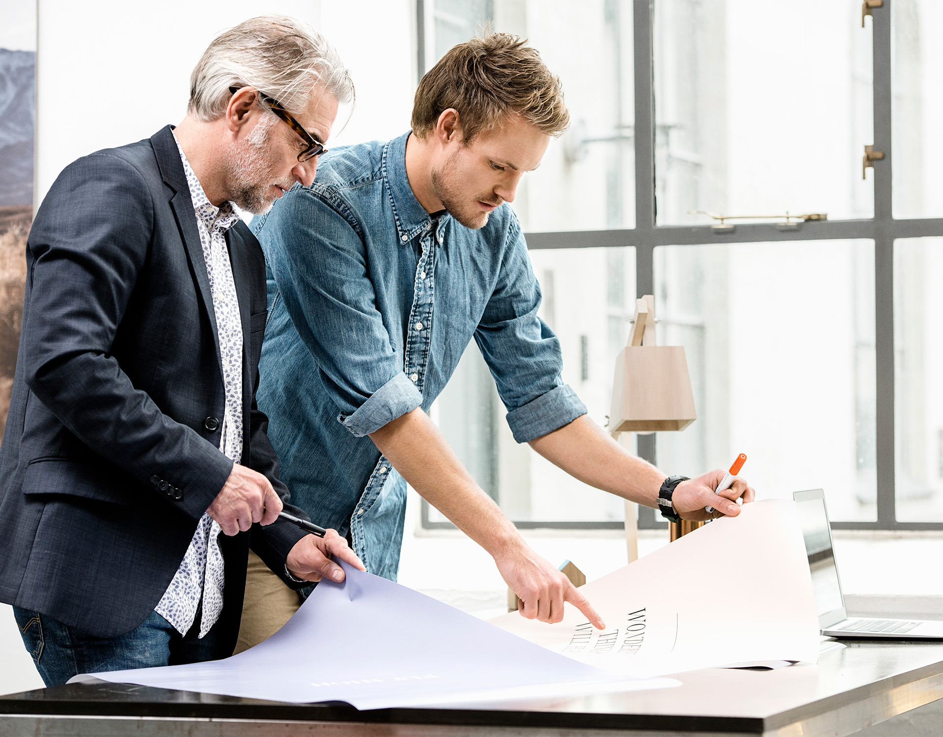 Zwei Berater kooperieren bei der Bearbeitung eines Dokuments in einem modernen Büro, was die projektbezogene Zusammenarbeit des Unternehmens im Consulting- und Investmentbereich zeigt.